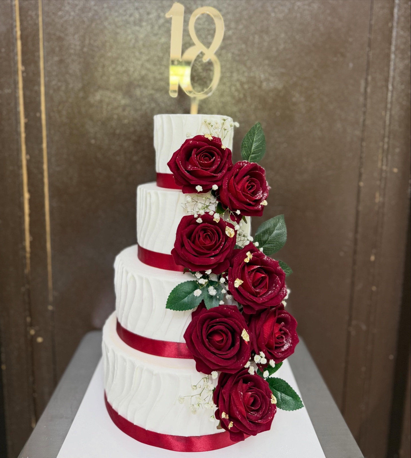Torta a quattro piani per un diciottesimo, bianca con rose rosse e nastri bordeaux